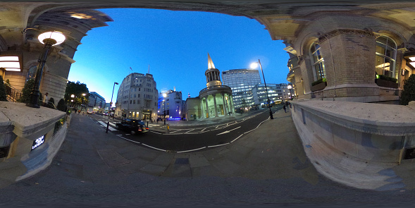 VR near BBC Centre in London with tourists and traffic. It is taken at night with lights on the BBC building and the monument outside.