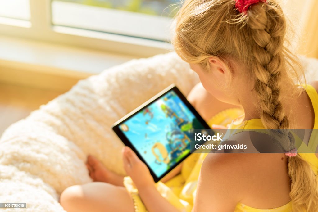 Girl playing game on tablet computer Unrecognizable girl playing game on tablet computer Child Stock Photo