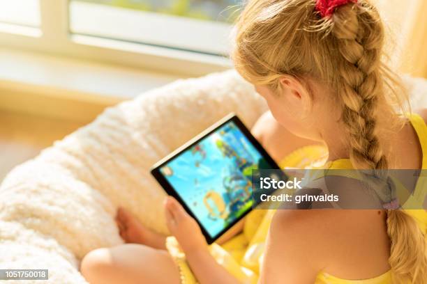 Girl Playing Game On Tablet Computer Stock Photo - Download Image Now - Child, Digital Tablet, Device Screen