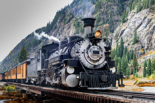 Vintage Steam Train Crossing a River in Colorado Steam Locomotive on a trestle bride, crossing a river in the mountains. steam train stock pictures, royalty-free photos & images