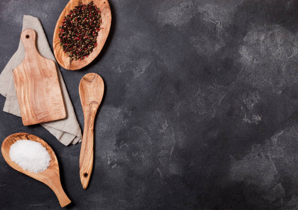 istock Olive wood kitchen utensils with chopping board and bowl on stone table background. Top view. Space for text 1051762022