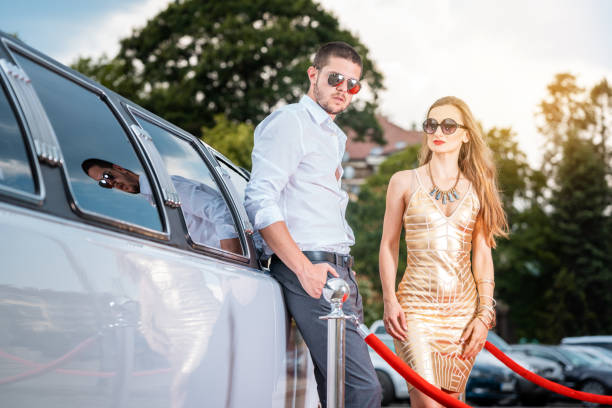 istock Woman and man leaning against a limo car 1051773702