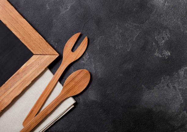 istock Vintage kitchen wooden utensils with chalk menu board on black stone table background. Top view. 1051773892