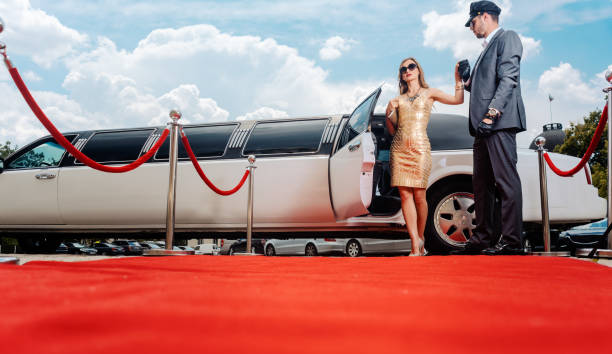 driver helping vip woman or star out of limo on red carpet - limousine imagens e fotografias de stock