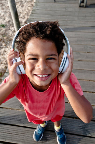 istock Young Boy Wearing A Headphone Posing On A Wooden Pier/Bridge 1051775990