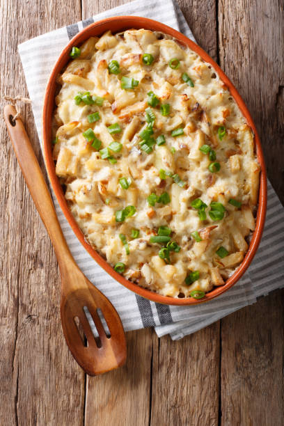 Portuguese food: casserole with cod, potatoes, onions and cream in a baking dish close-up. vertical top view Portuguese food: casserole with cod, potatoes, onions and cream in a baking dish close-up on the table. vertical top view from above com stock pictures, royalty-free photos & images