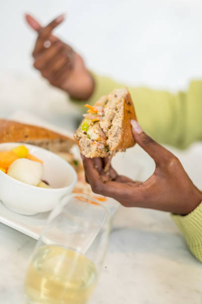 Close up of the hands of Young black woman while having lunch at the urban coffee shop. Focus on the sandwich in her hand.