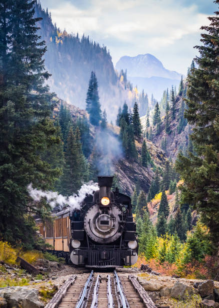 Steam Train Crossing a Trestle Bridge in the Mountains Steam Locomotive on a trestle bride, crossing a river in the mountains. locomotive stock pictures, royalty-free photos & images
