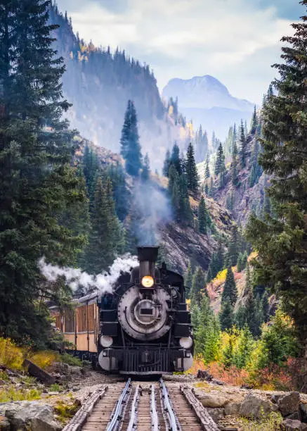 Steam Locomotive on a trestle bride, crossing a river in the mountains.