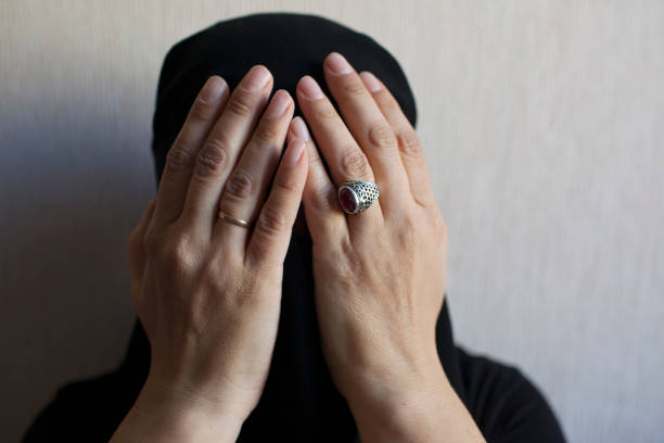 Woman in black niqab holds her head with her hands