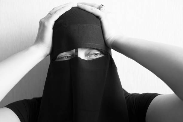 istock Woman in niqab holds her head with her hands 1051797822
