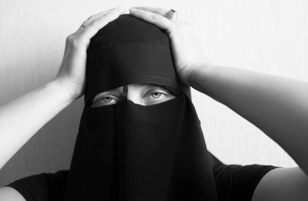 istock Woman in niqab holds her head with her hands 1051797834
