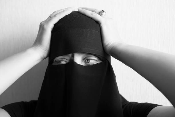 istock Woman in niqab holds her head with her hands 1051797850