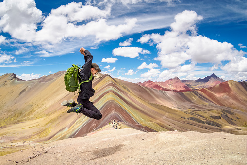 Saltando en la cima de la montaña de arco iris en Cusco, Perú. photo