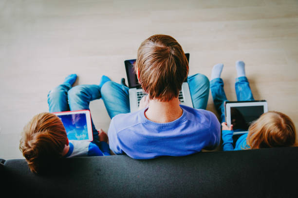istock father with kids using laptop and tablet, modern technology at home 1051802482