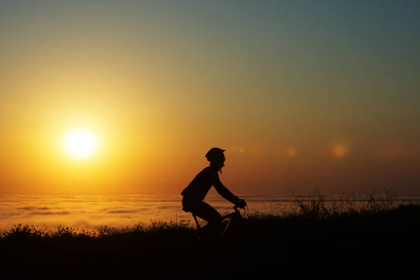 A woman goes for a bike ride at low tide on Long Beach on Vancouver Island near Tofino, British Columbia, Canada, at sunset. At low tide, when the sand is firm, it is possible to ride the length of Long Beach on most any kind of bicycle.