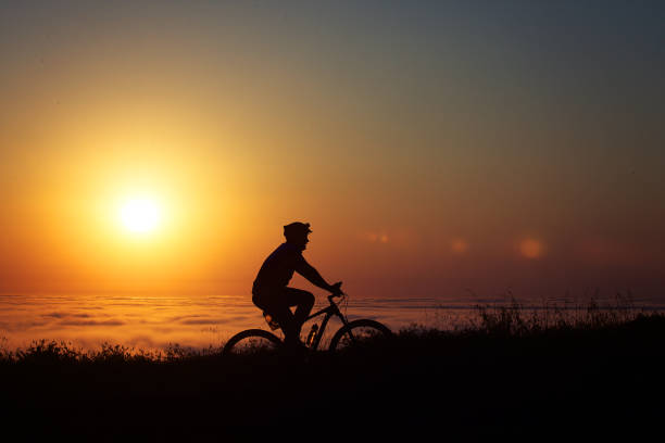 Silhouette of a cyclist mountain biking high above the clouds at sunset Cape Town South Africa