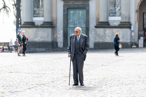 シニア高齢者老人の杖で有名な広場、ドゥオーモ、単独での歩行をイタリアの伝統的な衣装のスーツ、ベスト、杖、服を着てください。 - human hand aging process senior adult cane ストックフォトと画像