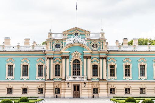 Kyiv, Ukraine - August 12, 2018: Ukrainian building called Mariyinsky Dvorec with flag, Castle Park exterior of historic blue building entrance