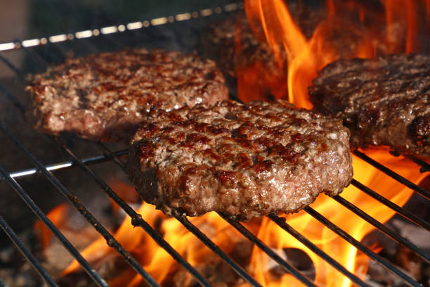 Beef burger for hamburger on barbecue flame grill Close up beef or pork meat barbecue burgers for hamburger prepared grilled on bbq fire flame grill, high angle view burger stock pictures, royalty-free photos & images