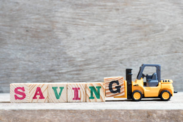 istock Toy forklift hold letter block g to complete word saving on wood background 1051871404