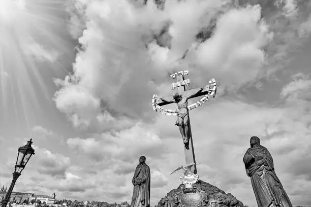 Photo of Jesus Crucifixion statue with Hebrew lettering in Charles Bridge Prague, Czech Republic. Black and white