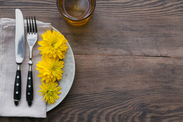 istock Rustic table setting with linen napkin, cutlery, ceramic plates, yellow glasses and yellow flowers 1051954214