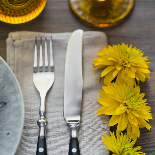 istock Rustic table setting with linen napkin, cutlery, ceramic plates, yellow glasses and yellow flowers 1051954242