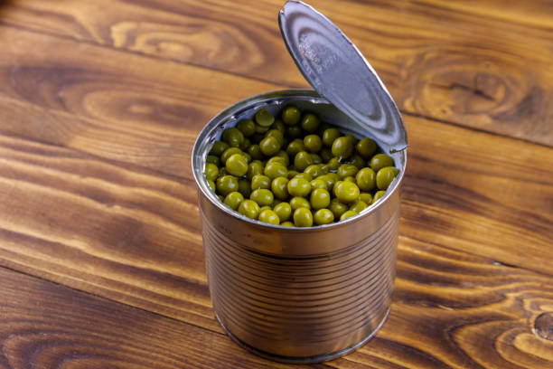 istock Open tin can of green peas on wooden table 1051971460