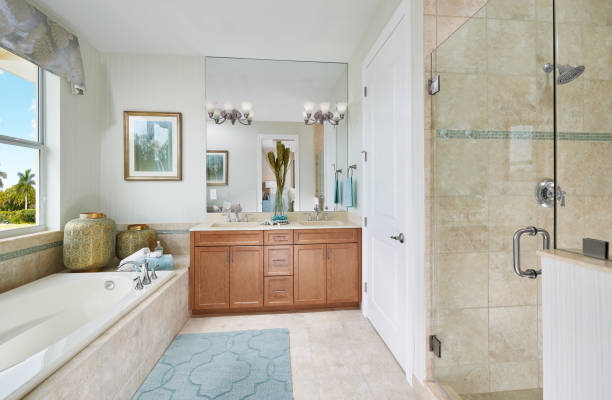 A Blue, Brown, and White Tropical Master Bathroom with a large Mirror in a Model Home