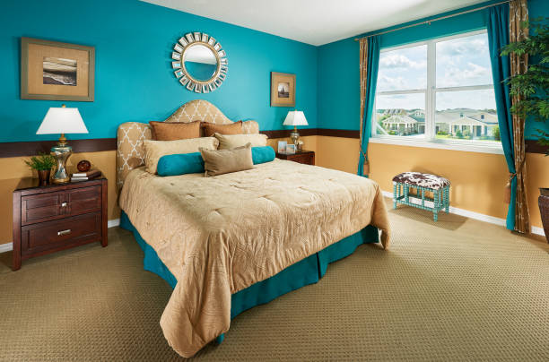 A Blue, Brown, and Tan Master Bedroom with a Sun Mirror in a Model Home stock photo