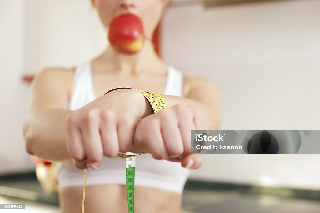 Diet - woman gagged and handcuffed Woman handcuffed by a tape measure and gagged by an apple - symbol for eating disorder Gag Stock Photo