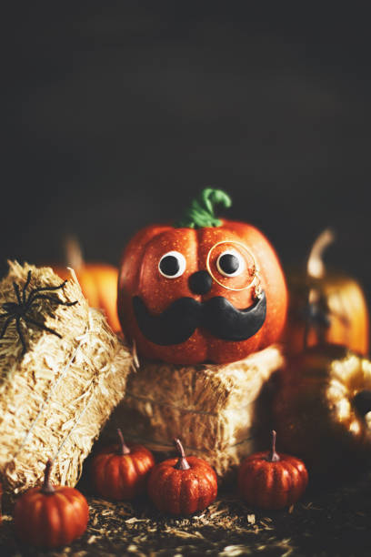 istock Pumpkin gentleman character with handmade features and monocle on straw bales 1052005900
