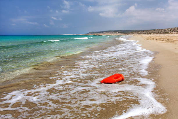 Bright red plastic oil (or washing liquid) container on beautiful unspoiled beach. Ocean plastics littering concept. Karpazz, Northern Cyprus.