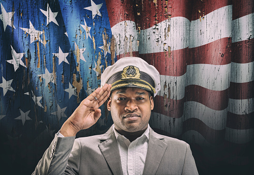 US boat captain saluting in front of American flag