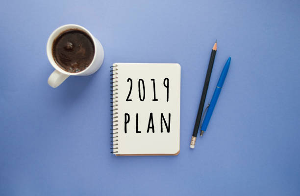 istock Notepad, pens and a cup of coffee on purple background. 1052031558