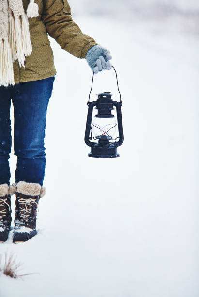istock Woman holding old fashioned lantern in snowy landscape 1052049322