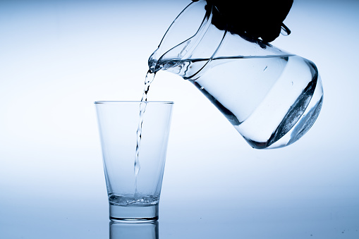 Close up pouring drinking water into glass, studio shot