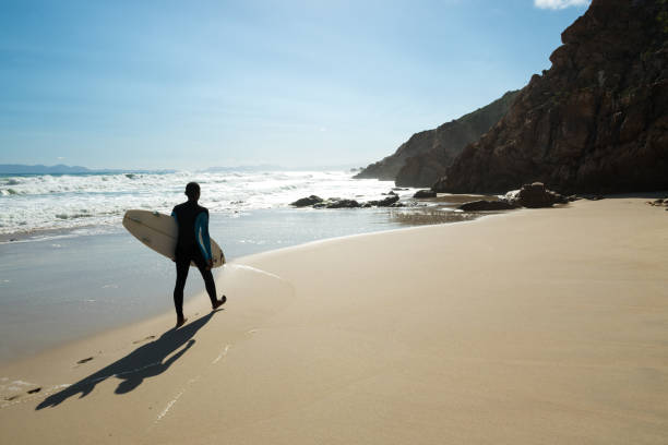 istock Man going surfing along a stunning coastline 1052172496
