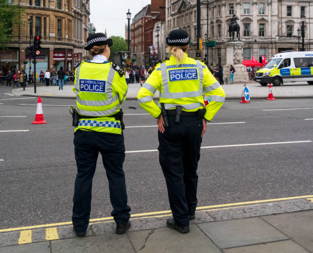 Female police officers on duty in London Two female Metropolitan Police officers standing roadside in Trafalgar Square opposite Northumberland Avenue on a rather gloomy day. metropolitan police stock pictures, royalty-free photos & images