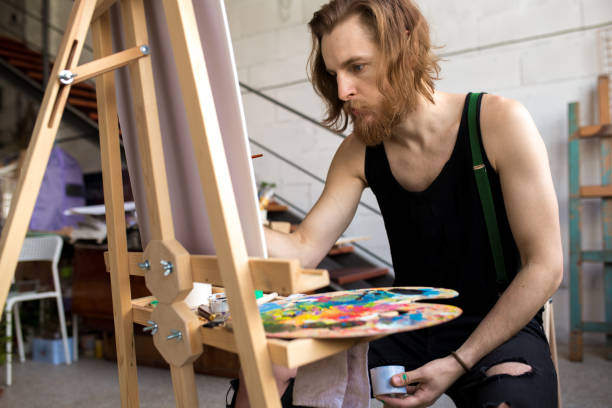 istock Bearded Artist Painting on Easel 1052177158