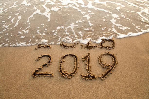 istock New year 2019 and 2018 on sandy beach with waves 1052203144