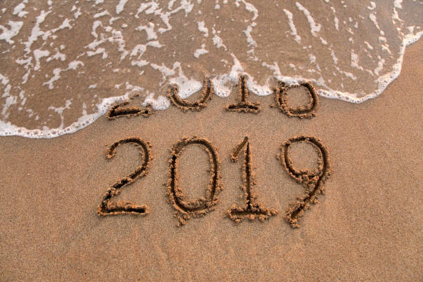 istock New year 2019 and 2018 on sandy beach with waves 1052204496