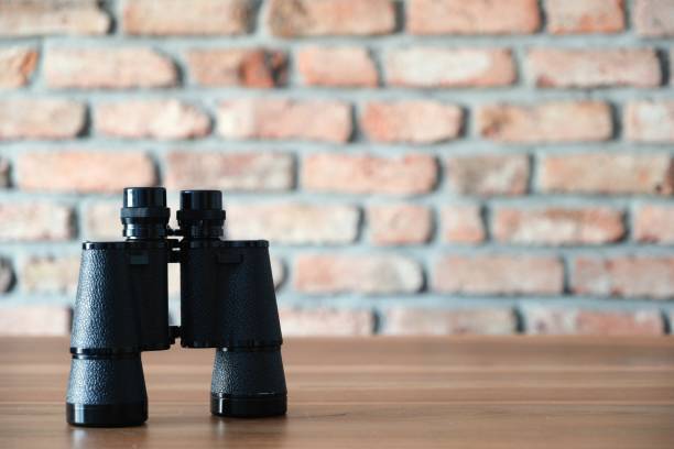 istock Retro old style black binoculars on wooden desk 1052205230
