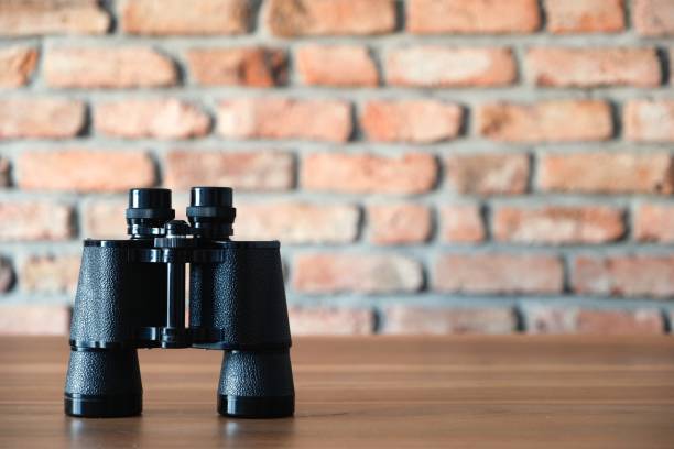 istock Retro old style black binoculars on wooden desk 1052205474
