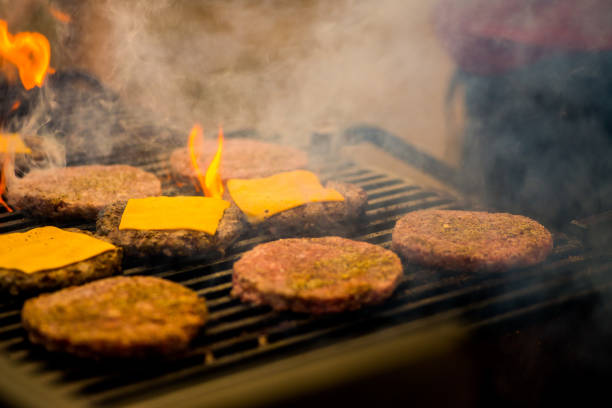 guy is cooking a cutlet with cheese for burgers on an open fire