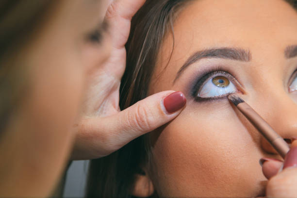 istock Beautiful fashion model applying makeup by makeup artis 1052276292