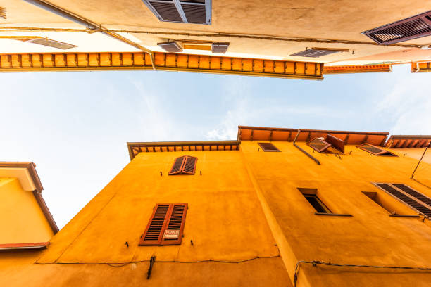 Chiusi, Italy street in small historic medieval town village in Umbria near Tuscany looking up, low angle view during sunny summer day, nobody, orange yellow bright vibrant colorful painted walls calle de chiusi, italia en pequeño pueblo medieval histórico pueblo en umbría cerca de toscana mirando hacia arriba, vista de ángulo bajo durante el día de verano soleado, nadie, naranja amarillo brillante vibrante colorido pintado las paredes
