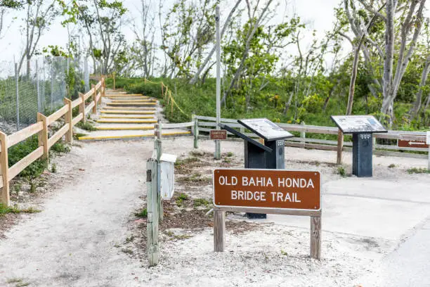 Sign for Old Bahia Honda Bridge Trail in state park during day sunset evening in Florida Keys, with hiking path