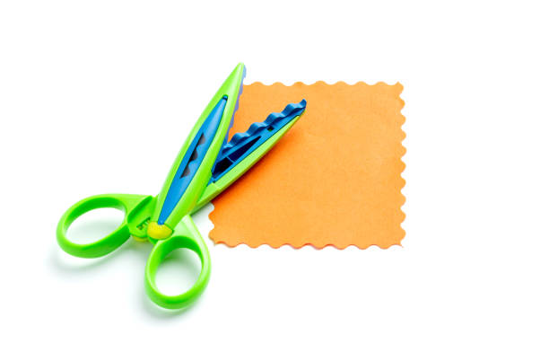 A sheet of orange paper with a wavy edge lies on a white background near the curly scissors. Creativity, playing with children at home and in kindergarten A sheet of orange paper with a wavy edge lies on a white background near the curly scissors. Creativity, playing with children at home and in kindergarten. hi res stock pictures, royalty-free photos & images